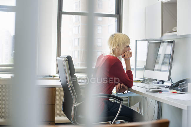 Жінка сидить за столом за допомогою комп'ютера — стокове фото