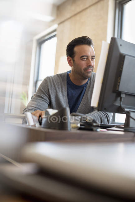 Homem sentado em uma mesa usando um computador . — Fotografia de Stock