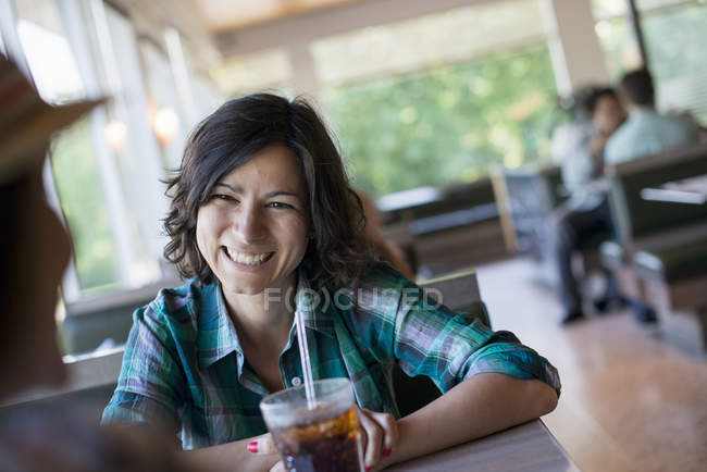 Woman seated holding a cold drink — Stock Photo