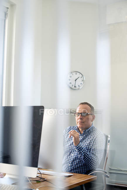 Hombre sentado en un escritorio . - foto de stock