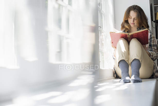 Woman seated by a window — Stock Photo