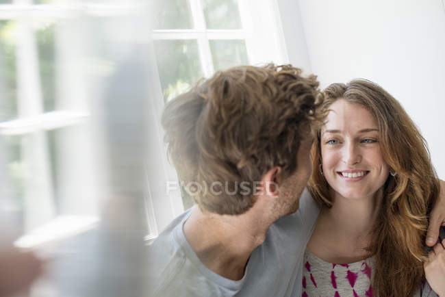 Couple embracing by a window. — Stock Photo