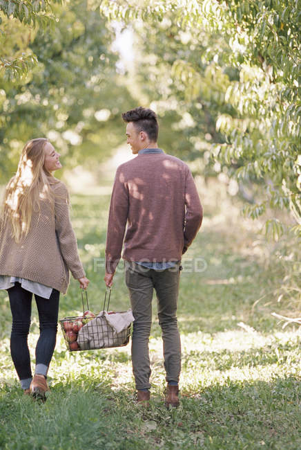Couple carrying a basket of apples. — Stock Photo