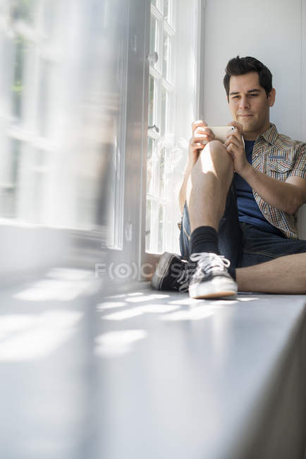Hombre sentado junto a una ventana - foto de stock