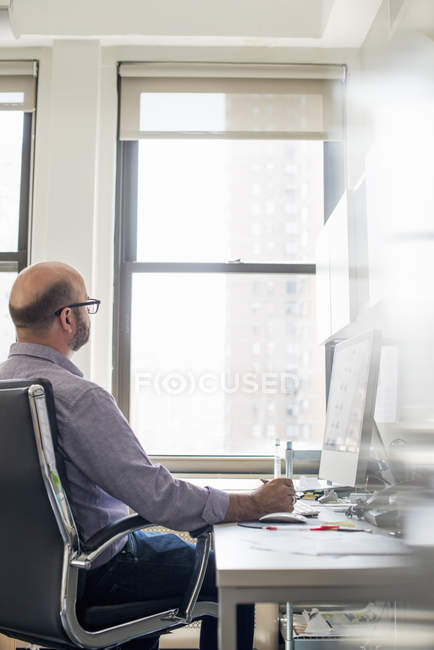 Hombre en la oficina usando un ordenador - foto de stock