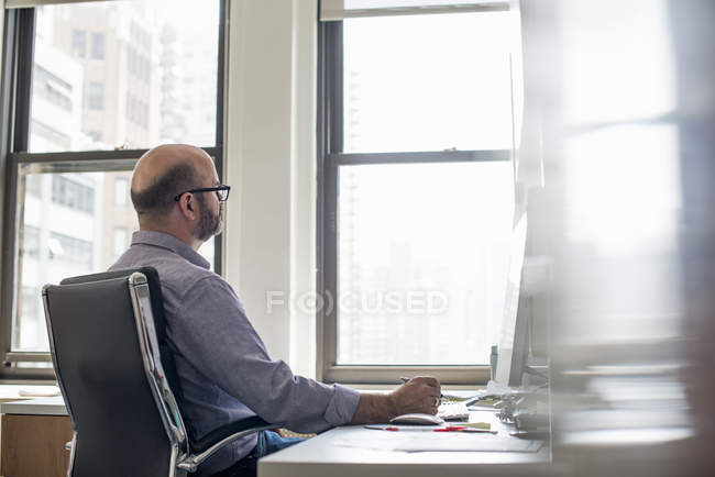 Человек в офисе с помощью компьютера — стоковое фото