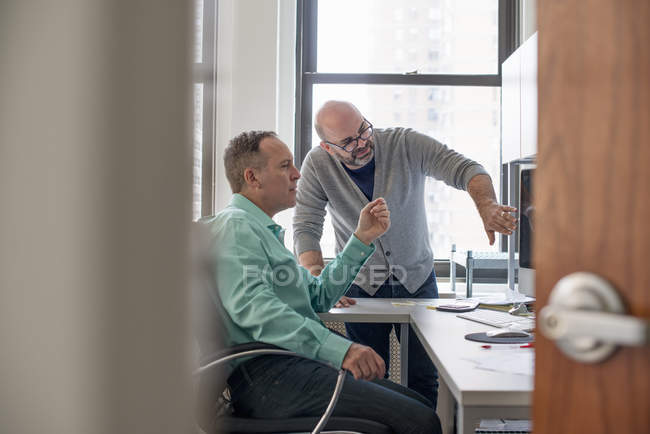 Homens em um escritório olhando para um computador — Fotografia de Stock