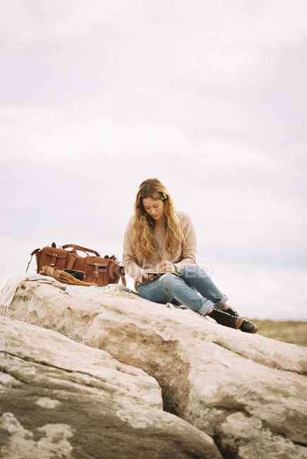 Donna seduta su una roccia — Foto stock