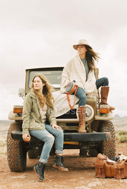 Women sitting on the front of a jeep — Stock Photo