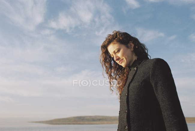 Frau mit lockigem Haar steht am See — Stockfoto