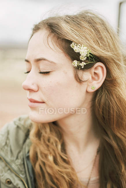Frau mit geschlossenen Augen mit Blumen im Haar — Stockfoto