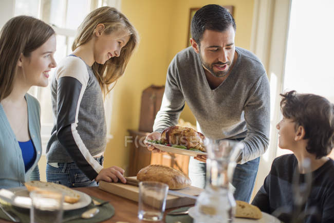 Adultos y niños reunidos alrededor de una mesa - foto de stock