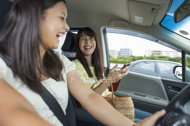 Madre e hija riendo en coche - foto de stock