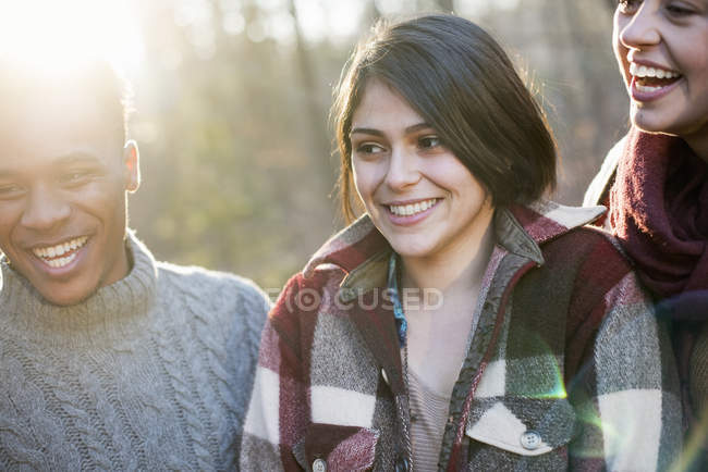 Women and man smiling in sunlit forest — Stock Photo