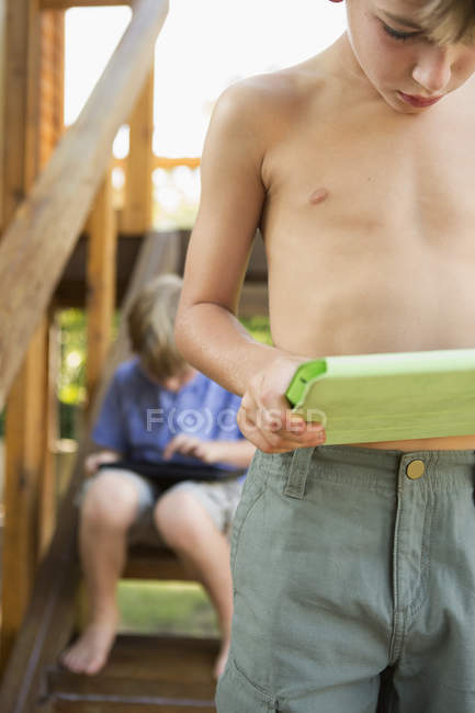 Brothers playing on their digital tablets — Stock Photo