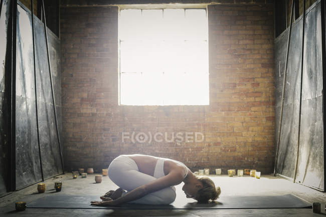 Mujer haciendo yoga rodeada de velas - foto de stock