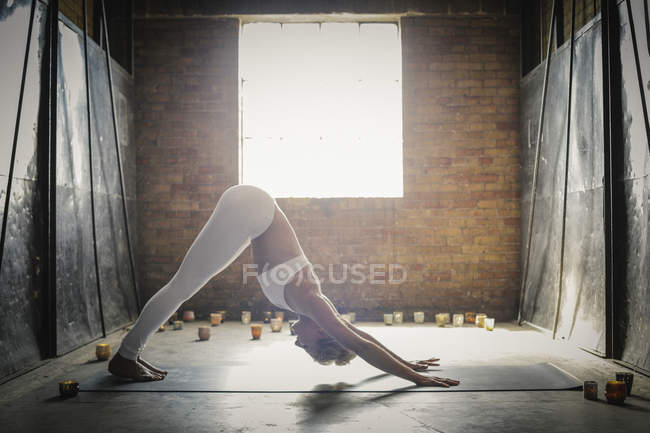 Mujer haciendo yoga rodeada de velas - foto de stock