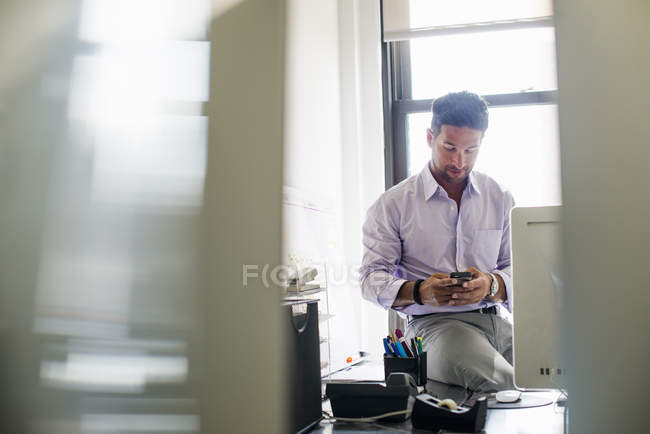 Mann checkt sein Handy im Büro. — Stockfoto