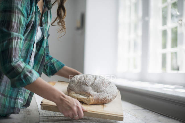 Woman carrying a fresh baked bread — Stock Photo