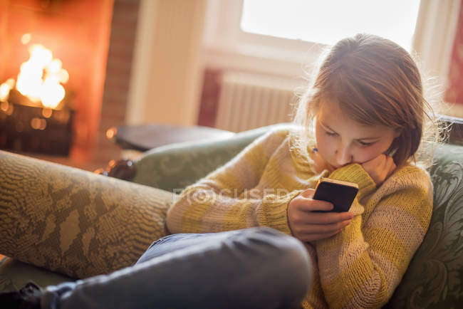 Chica sentada revisando su teléfono celular - foto de stock