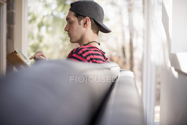 Man sitting backwards on sofa with tablet — Stock Photo