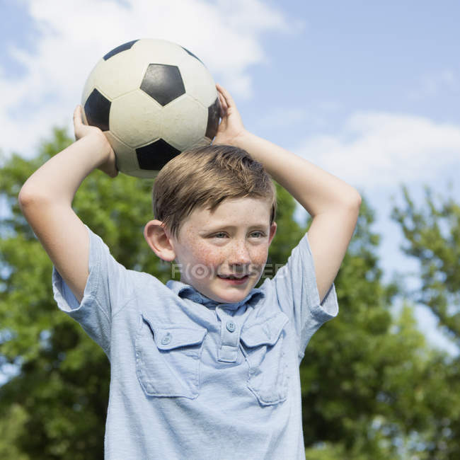 Niño sosteniendo una pelota de fútbol - foto de stock