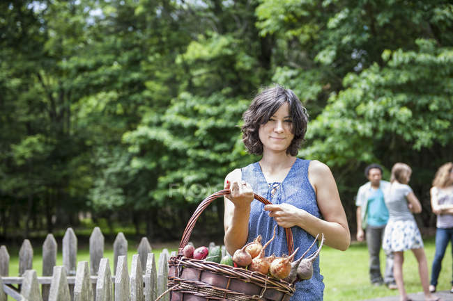 Mujer sosteniendo una cesta en el jardín - foto de stock