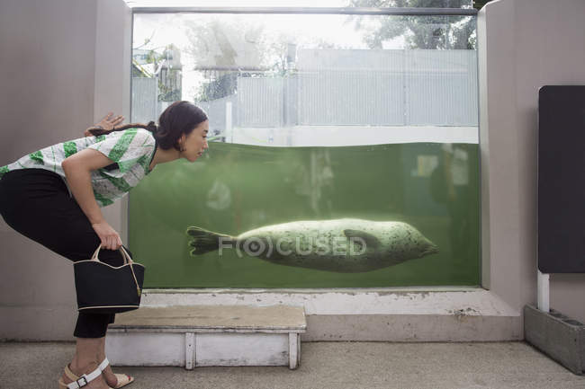 Woman crouching by marine tank — Stock Photo
