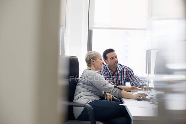 Colegas en una oficina mirando un ordenador - foto de stock