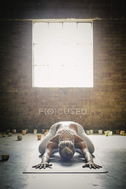Woman doing yoga surrounded by candles — Stock Photo