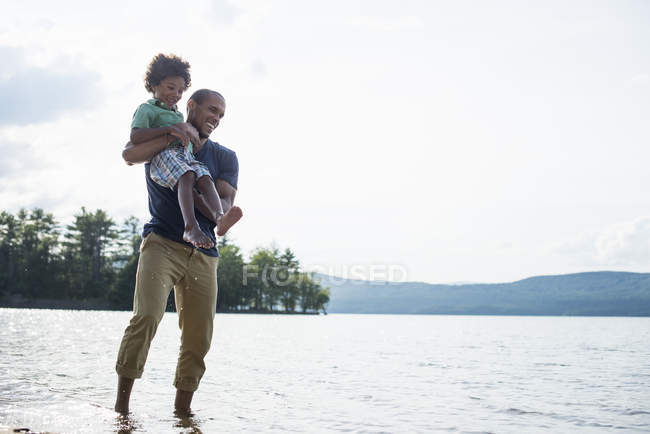 Padre e hijo en una orilla del lago - foto de stock