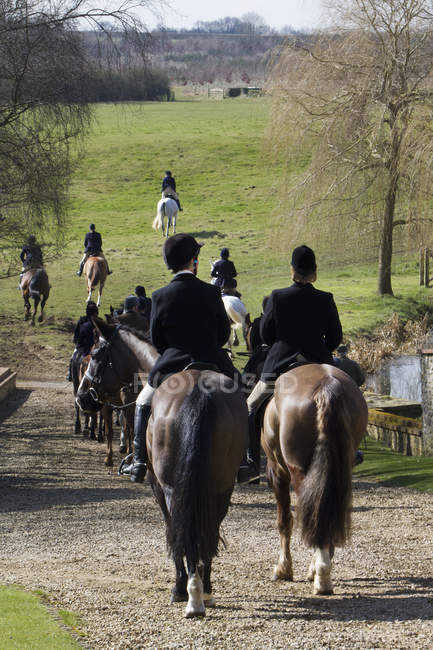 Cavaleiros montando através do campo — Fotografia de Stock