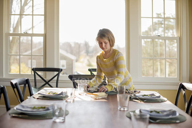 Chica poniendo la mesa con platos - foto de stock