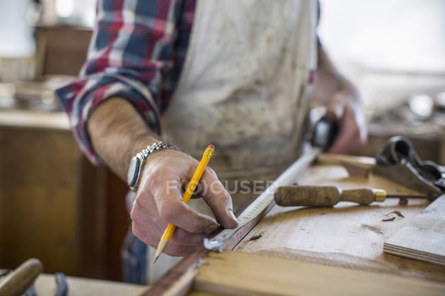 Antique furniture restorer measuring wood — Stock Photo