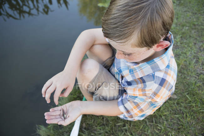 Молодий хлопчик сидить з маленькою рибою — стокове фото
