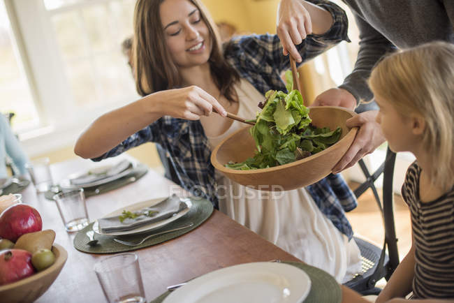 Mujer joven poniendo ensalada - foto de stock