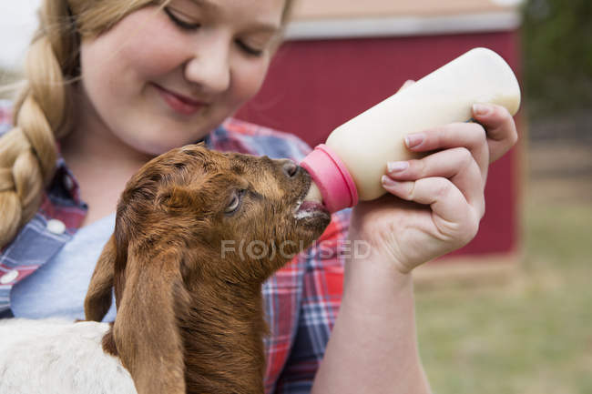 Mädchen füttert ein Ziegenbaby. — Stockfoto