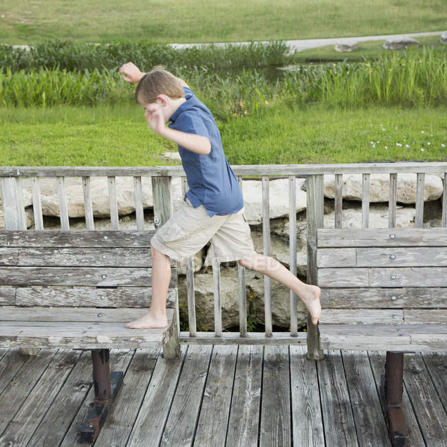 Menino pulando de um banco para outro — Fotografia de Stock