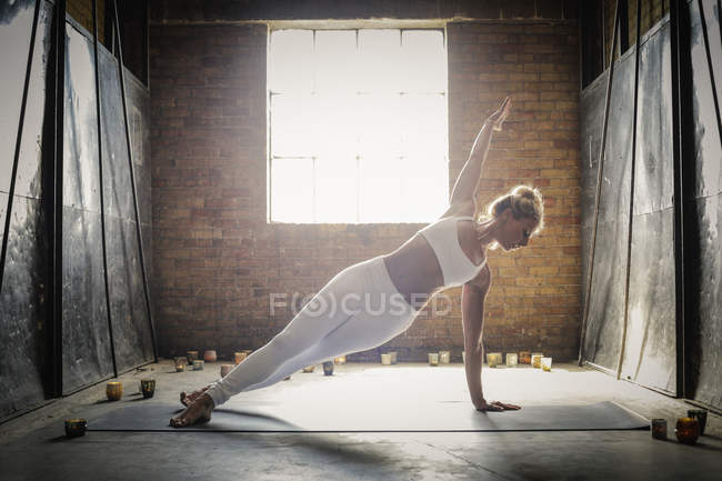 Жінка робить йогу в оточенні свічок — стокове фото