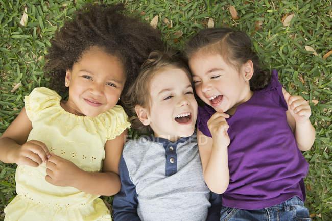Kinder liegen auf dem Gras und lachen — Stockfoto