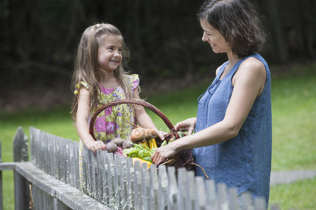 Mother and daughter with basket of vegetables. — Stock Photo