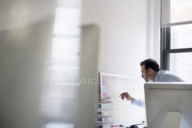 Hombre usando un bolígrafo para marcar un gráfico de pared - foto de stock