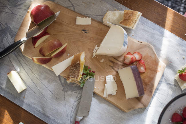 Chopping board with cheeses, apples and bread — Stock Photo