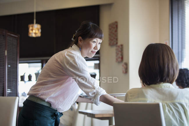 Waitress serving woman in cafe — Stock Photo