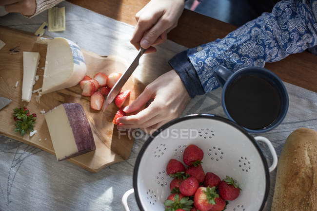 Femme tranchant des fraises sur une table — Photo de stock