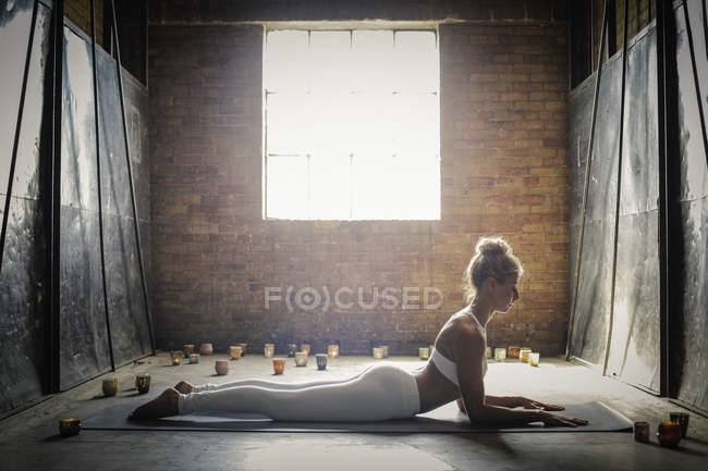 Mulher fazendo ioga cercada por velas — Fotografia de Stock