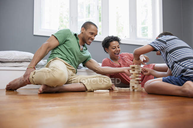 Familia en el suelo jugando un juego - foto de stock