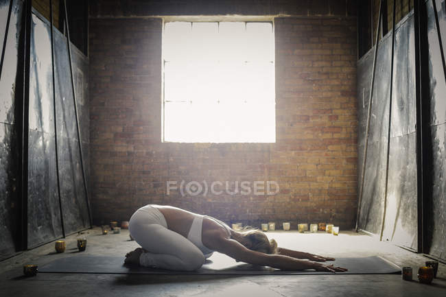 Mulher fazendo ioga cercada por velas — Fotografia de Stock