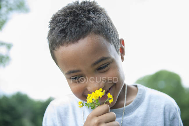 Niño sonriendo y sosteniendo la flor . - foto de stock