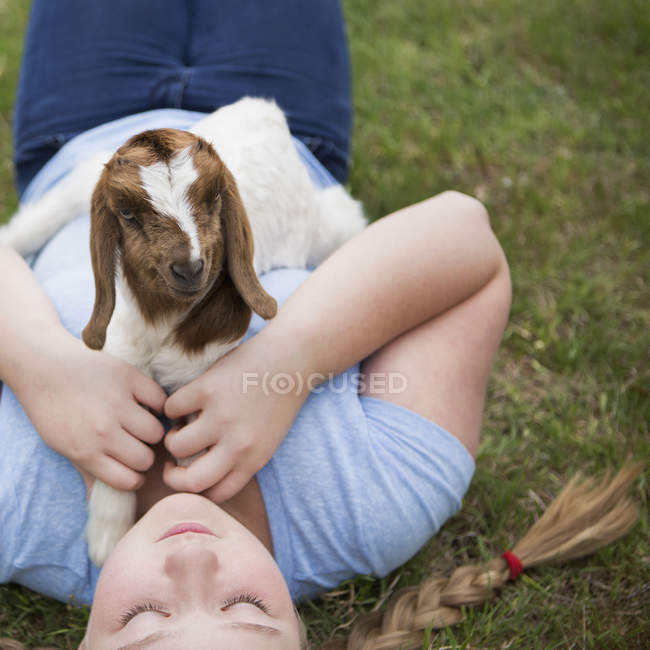 Menina abraçando um bebê cabra — Fotografia de Stock